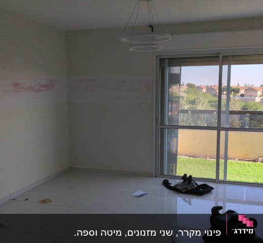 חדר ריק עם חלון גדול וכלים על הרצפה